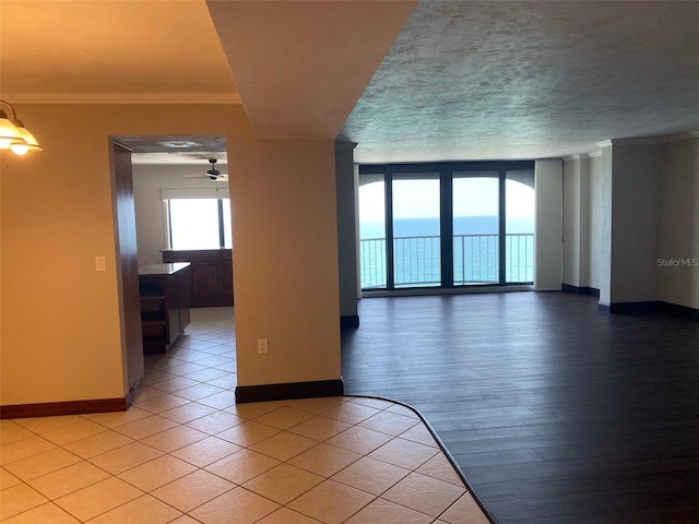 spare room with a textured ceiling, light hardwood / wood-style flooring, a water view, crown molding, and ceiling fan