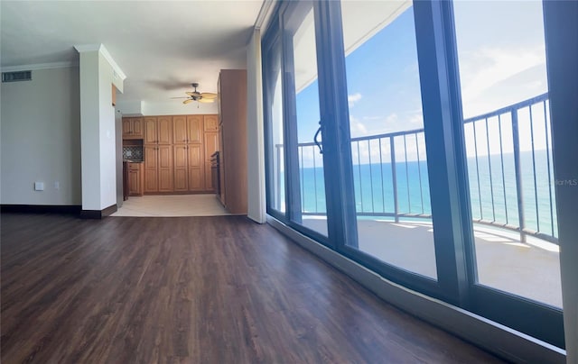 unfurnished living room with ornamental molding, a water view, ceiling fan, and dark hardwood / wood-style flooring