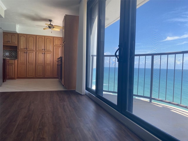 interior space with ceiling fan, plenty of natural light, dark hardwood / wood-style flooring, and a water view