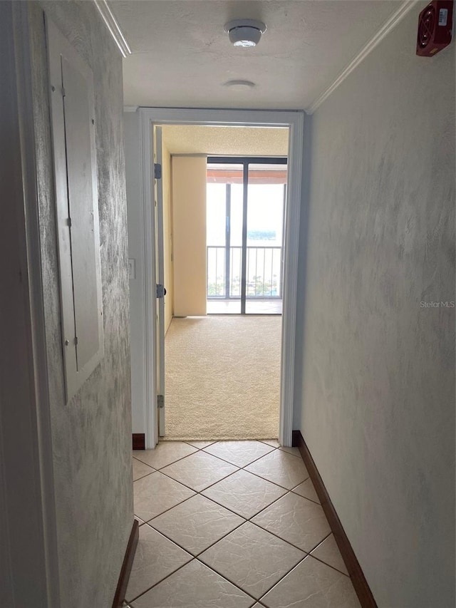 hallway featuring ornamental molding and light tile patterned floors