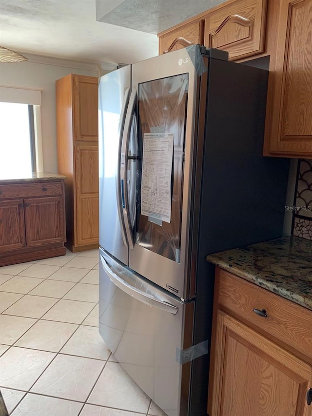 kitchen with stone counters, stainless steel refrigerator with ice dispenser, and light tile patterned flooring