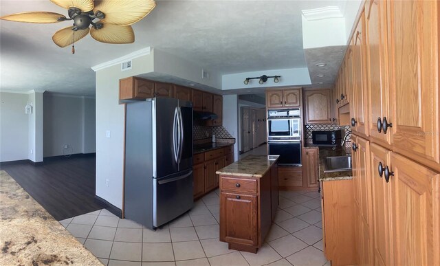 kitchen with appliances with stainless steel finishes, light tile patterned floors, crown molding, ceiling fan, and sink