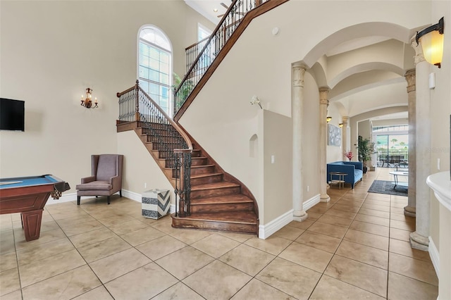 stairway with billiards, plenty of natural light, ornate columns, and a high ceiling