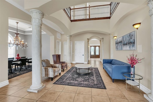 living room with decorative columns, an inviting chandelier, light tile patterned floors, ornamental molding, and a high ceiling