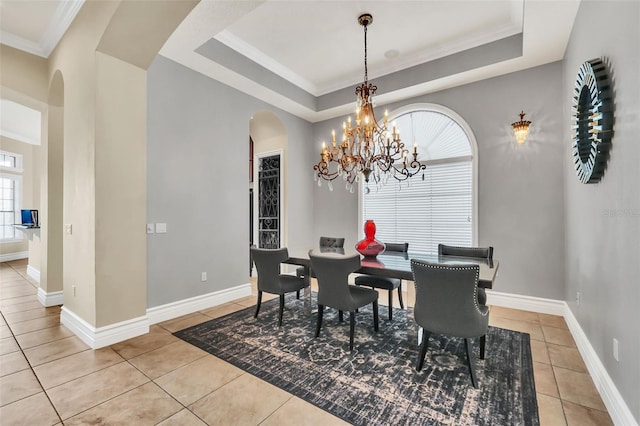 tiled dining area with ornamental molding, a raised ceiling, and plenty of natural light