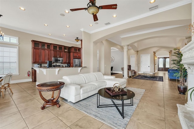 tiled living room featuring ornamental molding, ceiling fan with notable chandelier, and ornate columns