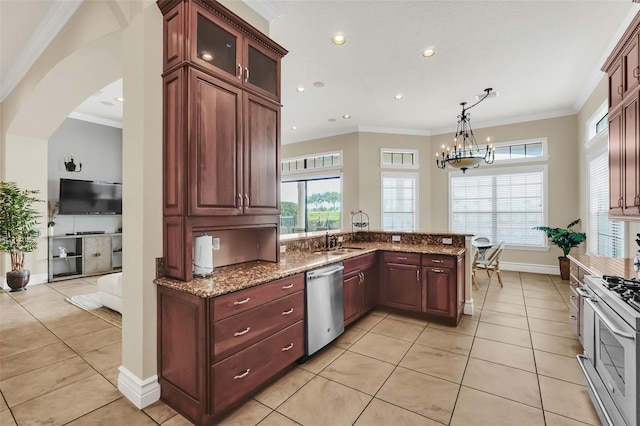 kitchen with kitchen peninsula, an inviting chandelier, appliances with stainless steel finishes, light tile patterned floors, and ornamental molding