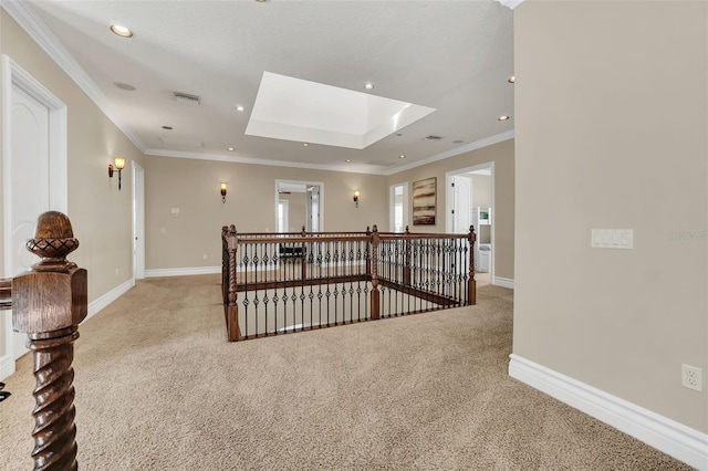 corridor featuring light carpet, a skylight, a raised ceiling, and ornamental molding