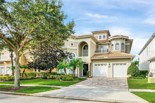 mediterranean / spanish home featuring a balcony, a garage, and a front yard