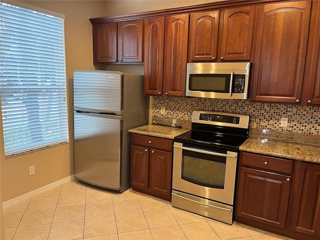 kitchen with appliances with stainless steel finishes, tasteful backsplash, light stone counters, and light tile patterned flooring