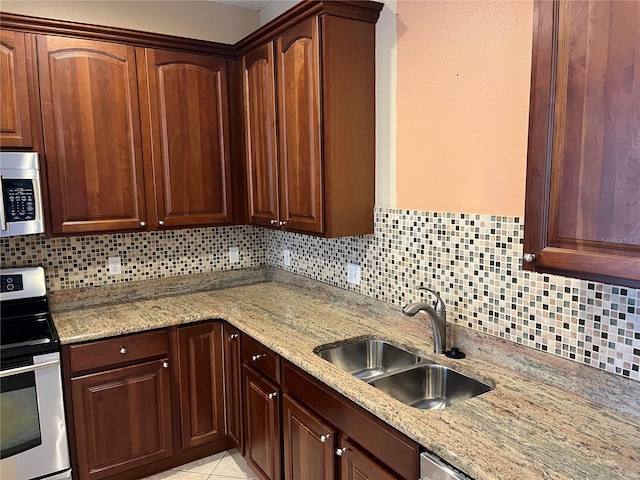 kitchen featuring light stone countertops, stainless steel appliances, tasteful backsplash, and sink