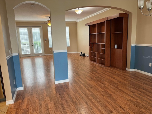 empty room featuring french doors, hardwood / wood-style floors, a textured ceiling, ceiling fan with notable chandelier, and ornamental molding