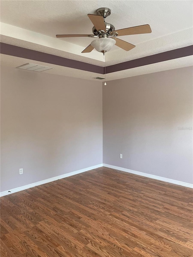 unfurnished room with a textured ceiling, dark hardwood / wood-style floors, and ceiling fan