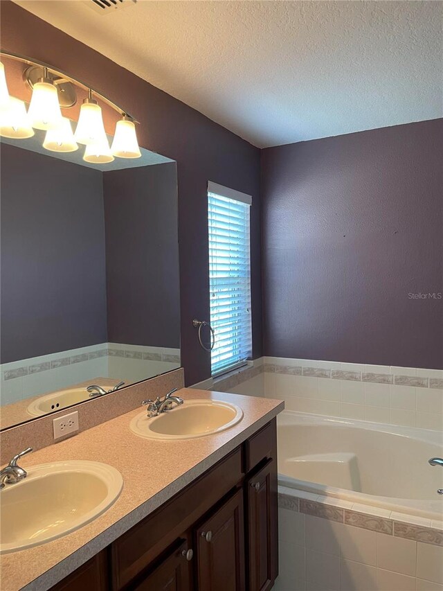 bathroom with vanity and tiled tub