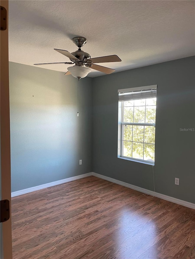 unfurnished room with a textured ceiling, ceiling fan, and dark wood-type flooring