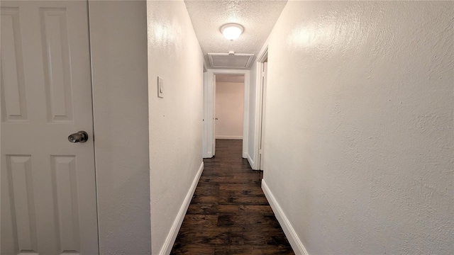 corridor with a textured ceiling and dark hardwood / wood-style floors