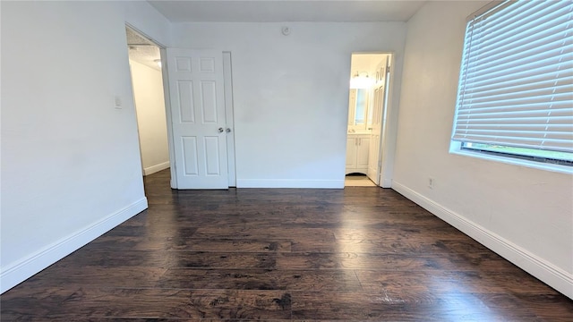 unfurnished bedroom featuring dark wood-type flooring and ensuite bath