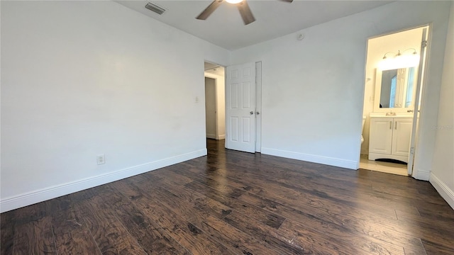 unfurnished bedroom featuring connected bathroom, dark wood-type flooring, and ceiling fan