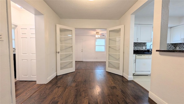 unfurnished dining area with ceiling fan, a textured ceiling, and dark hardwood / wood-style flooring