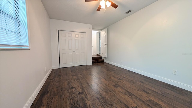 unfurnished bedroom featuring a closet, dark hardwood / wood-style floors, and ceiling fan