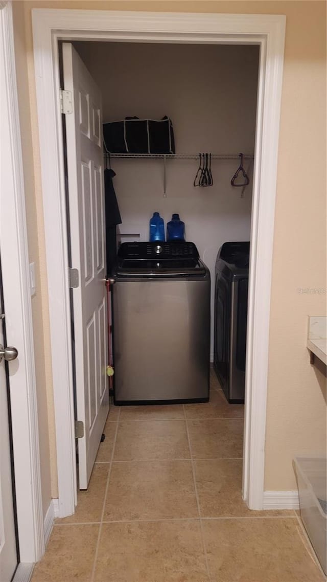 washroom with washer and clothes dryer and light tile patterned flooring