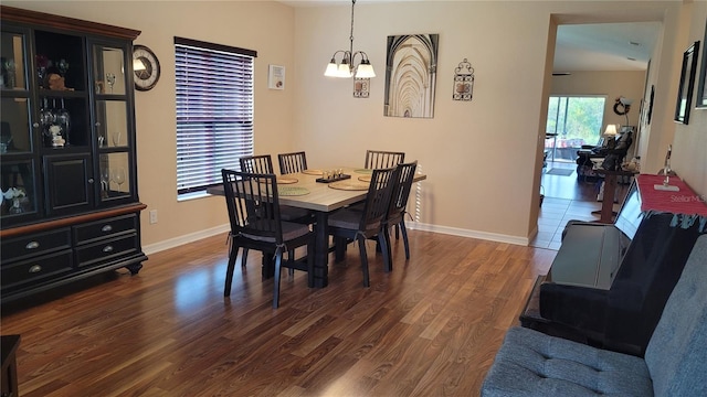 dining room with dark hardwood / wood-style floors and an inviting chandelier