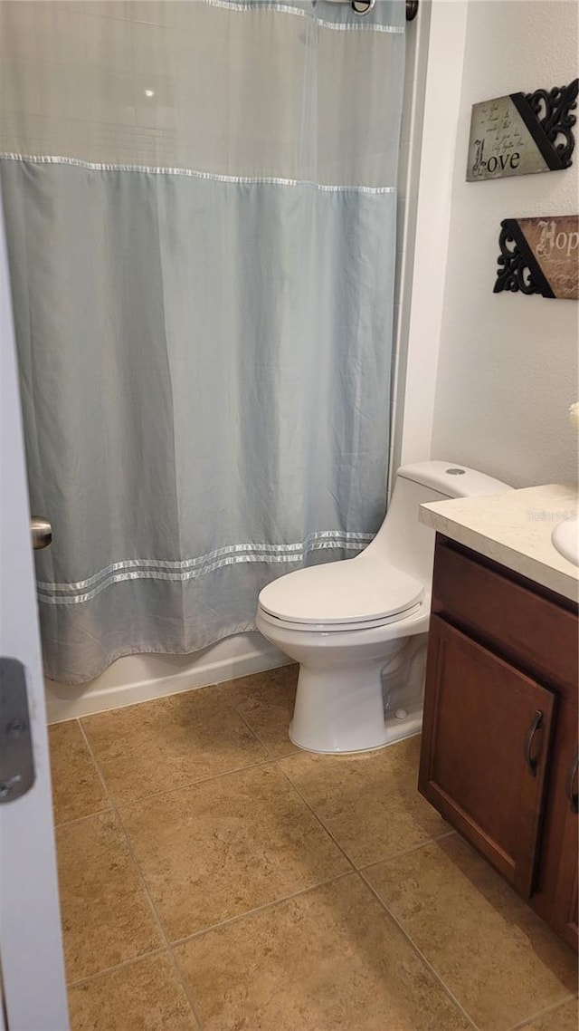 bathroom featuring toilet, vanity, a shower with shower curtain, and tile patterned flooring