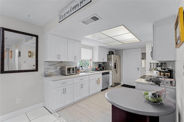 kitchen with backsplash, stainless steel appliances, sink, and white cabinets