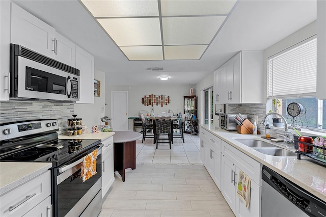 kitchen with appliances with stainless steel finishes, white cabinetry, tasteful backsplash, and sink