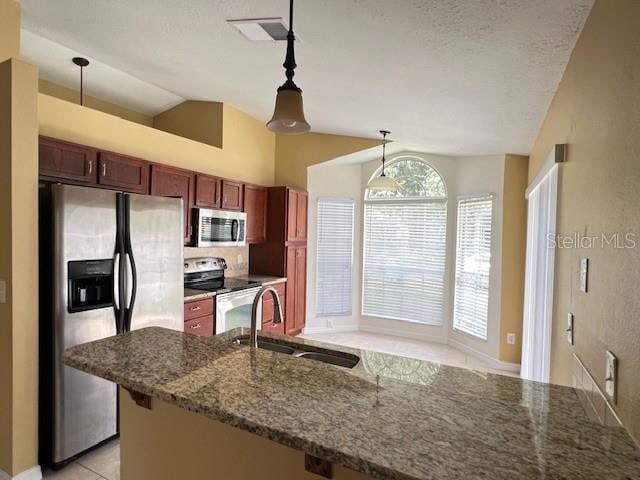 kitchen featuring sink, lofted ceiling, hanging light fixtures, appliances with stainless steel finishes, and dark stone countertops