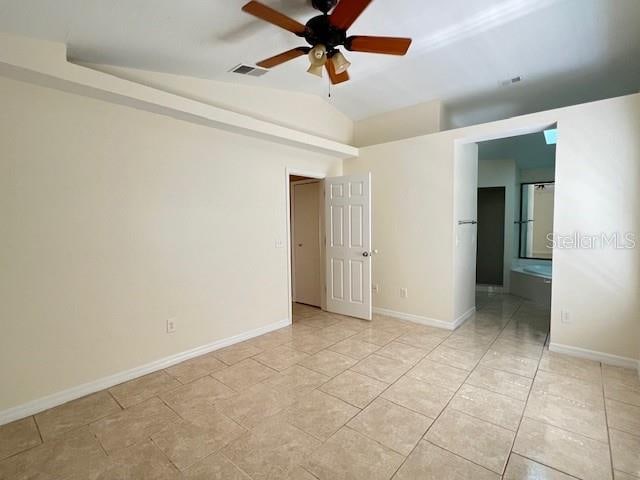 empty room with lofted ceiling, light tile patterned flooring, and ceiling fan