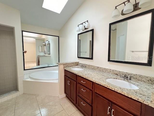 bathroom featuring shower with separate bathtub, tile patterned flooring, lofted ceiling with skylight, and vanity