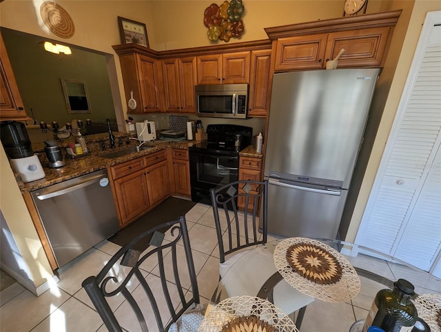 kitchen featuring light tile patterned flooring, appliances with stainless steel finishes, dark stone counters, and sink