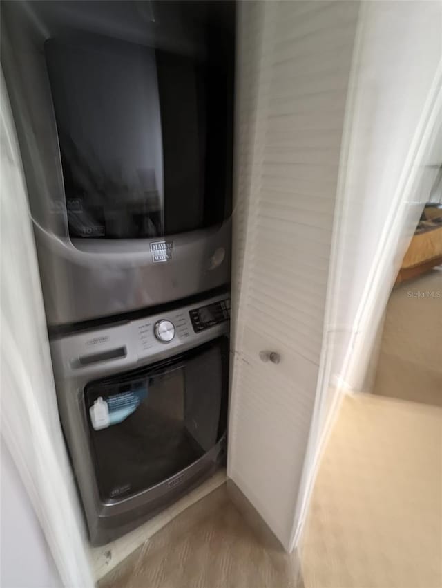 laundry area featuring wood-type flooring and stacked washer and clothes dryer