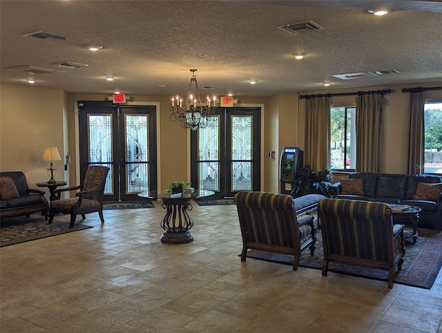 living room featuring a notable chandelier, a textured ceiling, and french doors