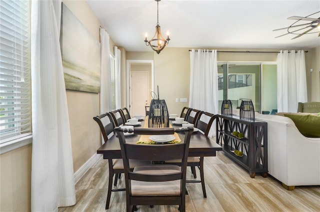 dining space with light hardwood / wood-style flooring and ceiling fan with notable chandelier