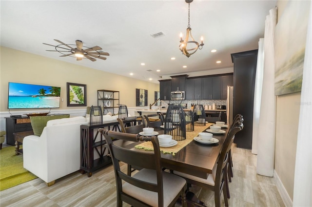 dining space featuring ceiling fan with notable chandelier and light hardwood / wood-style flooring