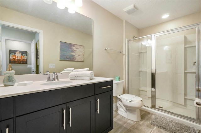 bathroom with wood-type flooring, vanity, toilet, and a shower with door