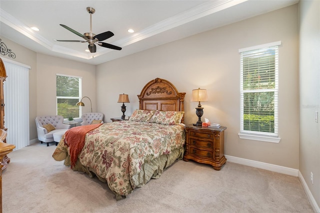 carpeted bedroom with ceiling fan, a tray ceiling, crown molding, and multiple windows