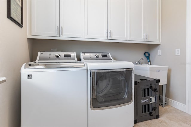 laundry room featuring light tile patterned flooring, separate washer and dryer, and cabinets