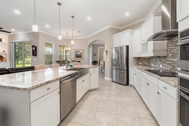 kitchen with wall chimney exhaust hood, a center island with sink, sink, stainless steel appliances, and white cabinets