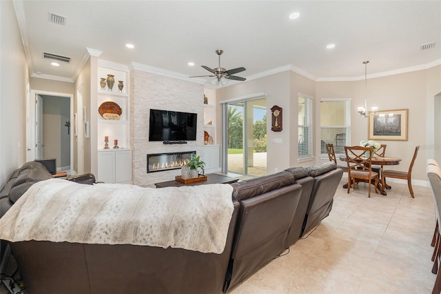 living room with a stone fireplace, ceiling fan with notable chandelier, crown molding, built in features, and light tile patterned floors