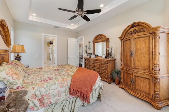 carpeted bedroom with a tray ceiling, ensuite bath, and ceiling fan