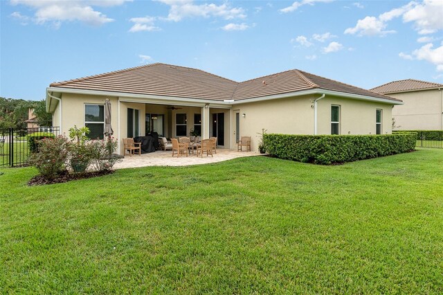 rear view of house with a yard, ceiling fan, and a patio