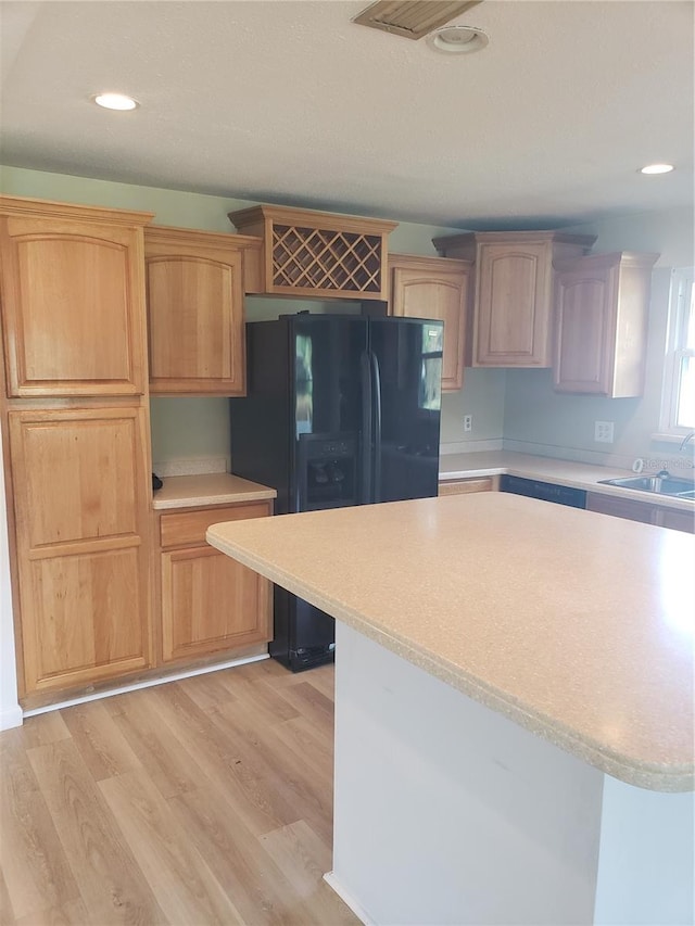 kitchen with black fridge, sink, and light hardwood / wood-style floors