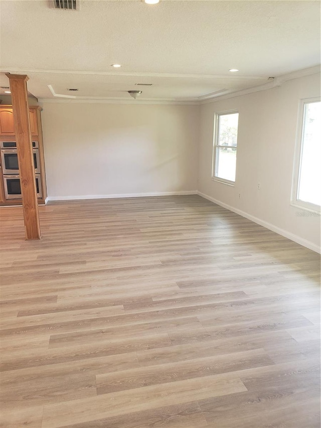 spare room featuring light wood-type flooring and crown molding