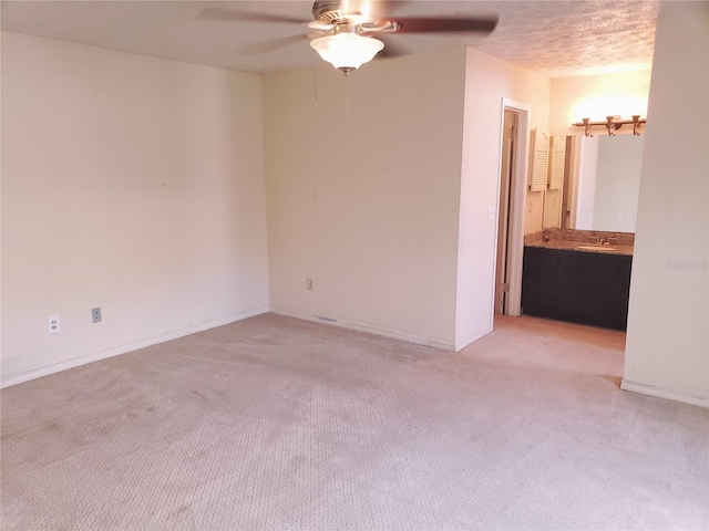 empty room featuring light carpet, ceiling fan, and a textured ceiling