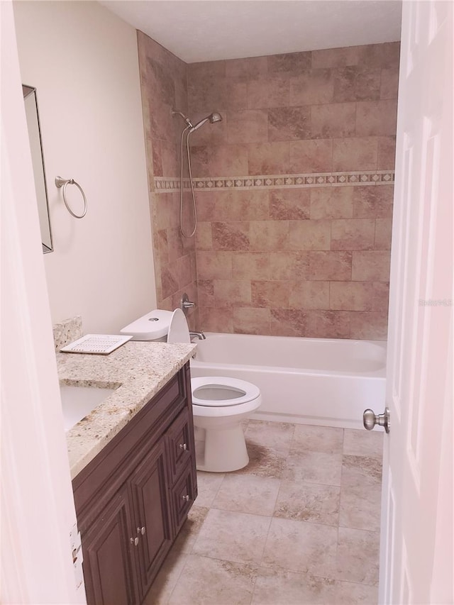 full bathroom featuring tiled shower / bath, vanity, and toilet