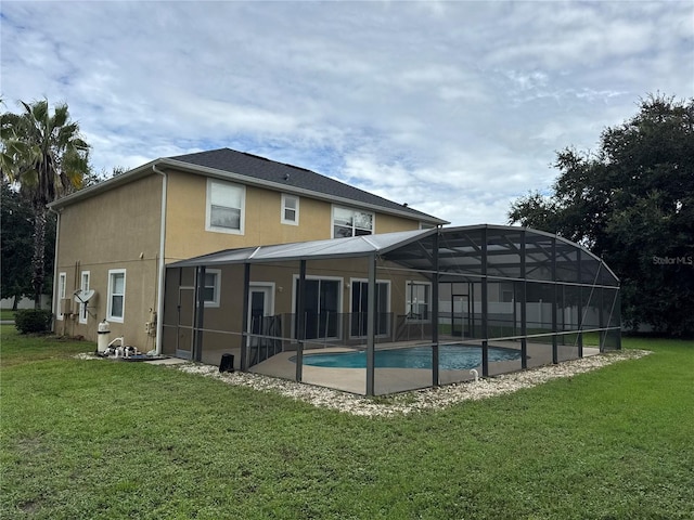 back of house featuring a yard, glass enclosure, and a patio area