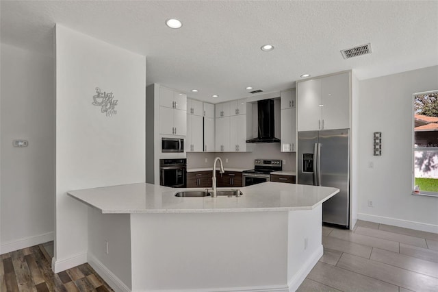 kitchen featuring wall chimney range hood, sink, stainless steel appliances, hardwood / wood-style flooring, and white cabinetry